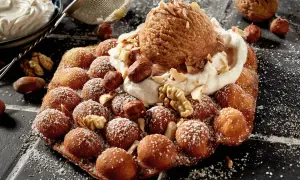 Bubble Eis auf einem Waffel-Snack, bestreut mit Puderzucker und garniert mit Nüssen und einer Kugel Eis.