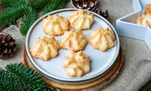 Leckere Kokosmakronen, die nach einem einfachen Rezept gelingen. Perfekt für die Weihnachtszeit, umgeben von Tannenzweigen und Zapfen.