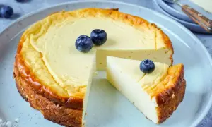 Ein cremiger Käsekuchen, perfekt für Diabetiker, mit frischen Blaubeeren garniert. Ein Stück wurde bereits entnommen.