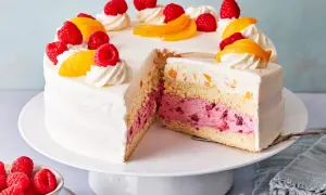 Eine köstliche Pfirsich Melba Torte mit saftigen Himbeeren und Pfirsichstücken, verziert mit Sahnetuffs.
