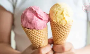 Zwei Eiswaffeln mit frucht eis: eine rosa und eine gelbe Kugel.