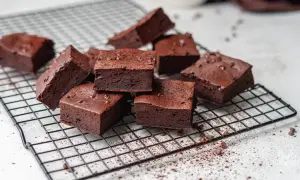 Saftige low carb brownies, bestreut mit Kakaopulver und Schokostückchen, auf einem Kuchengitter.