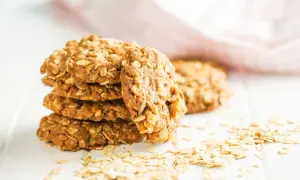 Gestapelte, goldbraune bananen haferflocken kekse mit Haferflocken verziert, liegen auf einem weißen Tisch.
