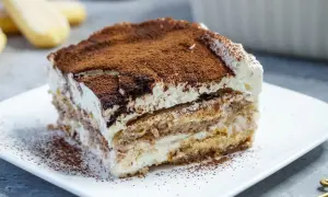 Ein Stück cremiges Tiramisu, bestäubt mit Kakao, perfekt für kleine Genießer.