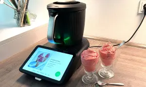 Moderne Eismaschine mit leckerem Heidelbeereis in Gläsern. Das Rezept wird auf dem Touchscreen angezeigt.