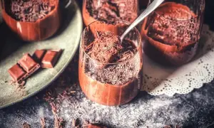Schokoladenmousse ohne Ei, garniert mit Schokostreuseln. Ein Löffel hebt eine Portion aus dem Glas.