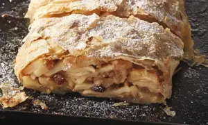 Ein saftiger Apfelstrudel, bestäubt mit Puderzucker, wartet darauf, nach diesem Rezept gebacken zu werden.