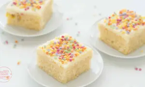 Drei Stücke saftiger konfetti kuchen mit weißer Glasur und bunten Streuseln auf weißen Tellern.