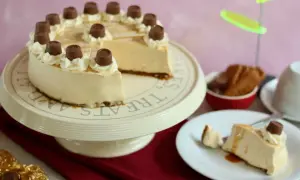 Eine köstliche Maxi King Torte, verziert mit Sahnetuffs und Schokostückchen, steht auf einem Tortenständer. Ein Stück ist bereits auf einem Teller angerichtet.