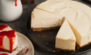 Ein cremiger ny cheesecake, auf einem Teller mit rotem Fruchttopping und ein weiterer auf einem schwarzen Teller, bereit zum Genießen.