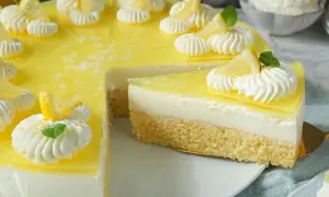 Eine köstliche zitronen torte mit Biskuitboden, cremiger Füllung und gelber Zitronenglasur, verziert mit Sahnetuffs und Zitronenspalten.