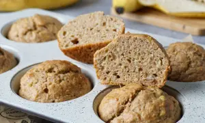 Saftige bananenmuffins ohne zucker, gebacken in einer Muffinform. Eine Hälfte ist aufgeschnitten und zeigt die lockere Krume.