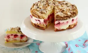 Himmlische Torte mit Baiser, Mandeln und Himbeercreme. Ein Stück ist bereits auf einem Teller angerichtet.