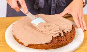Eine Schokoladentorte wird mit einer cremigen Füllung bestrichen, die an Kinder Bueno Torte erinnert.