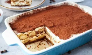 Ein cremiges Tiramisu, perfekt für ein tiramisu rezept ohne alkohol. Mit Kakaopulver bestäubt und in einer blauen Auflaufform serviert.