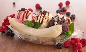 Ein köstlicher Bananensplit Eis mit drei Kugeln Eis, garniert mit Beeren und Minze.