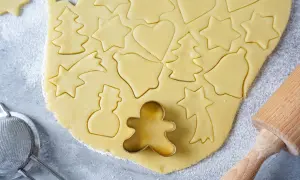 Ausgestochener Teig für Weihnachtsplätzchen mit Sternen, Herzen, Tannenbäumen und Schneemännern. Ein Ausstecher-Rezept für Spaß in der Küche.
