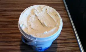 Ein Behälter mit cremigem, selbstgemachtem laktosefreiem Eis steht auf einer Holzoberfläche.
