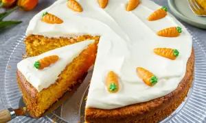 Ein saftiger Karottenkuchen mit weißem Zuckerguss und kleinen Marzipanmöhren. Perfekt für ein Osterkuchen Rezept!