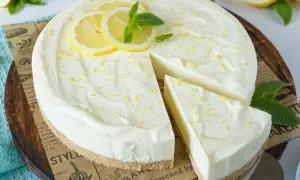 Cremige Philadelphia Torte mit Zitronenscheiben und Minze, ein Stück wurde bereits entnommen.