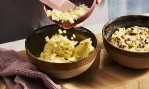 Zutaten für ein Crumble Cookie Rezept werden in Schüsseln gegeben: Teig mit Schokostückchen und weißer Schokolade.
