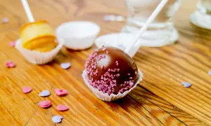 Schokoladen-Cake-Pops mit rosa Zuckerstreuseln und ein ungefüllter Cake Pop, bereit für ein einfaches cake pops rezept.