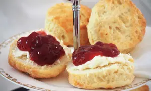 Zwei Scones mit Clotted Cream und Marmelade auf einer Etagere. Ein köstliches Rezept für Scones, das man unbedingt ausprobieren muss!