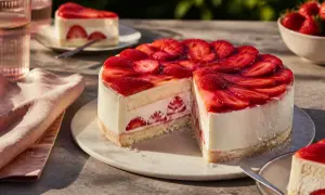 Eine köstliche Erdbeer Mascarpone Torte, üppig belegt mit frischen Erdbeeren und einem Hauch von Gelee. Ein Stück ist bereits angeschnitten.