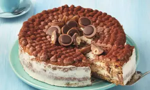 Eine köstliche Toffifee Torte, verziert mit Kakao und Toffifee-Pralinen, wird angeschnitten.