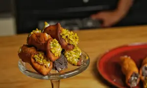 Ein Glasständer voller Cannoli, garniert mit Pistazien und Schokolade. Ein köstliches Cannoli-Rezept zum Nachmachen.