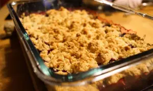 Frisch gebackener Himbeer Crumble in einer Glasform. Die goldbraune Kruste duftet verlockend nach Beeren und Streuseln.