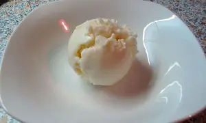 Ein Löffel cremiges Eis aus Quark in einer weißen Schale.