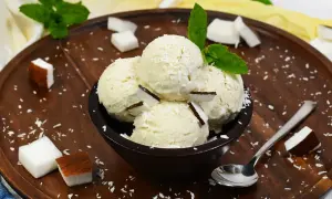 Schüssel mit Kokosnuss-Eis, garniert mit Kokosraspeln und Minze. Perfekt, um Kokosnuss Eis selber machen zu wollen!