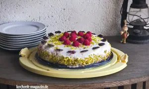 Himbeer Torte mit frischen Beeren, gehackten Pistazien und Schokoladenherzen verziert. Ein Genuss für jeden Anlass.
