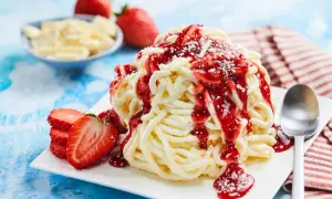 Ein köstliches Spaghetti-Eis mit Erdbeersoße und frischen Erdbeeren, bereit zum Genießen.