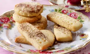 Leckeres Shortbread-Rezept: goldbraune Kekse, rund und rechteckig, mit Zimt und Zucker bestreut, auf einem floralen Teller.