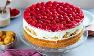 Eine köstliche Windbeuteltorte mit Himbeeren, geschichtet mit Sahne und Biskuit, verlockt zum Genuss.