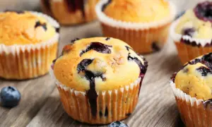 Saftige Blaubeermuffins, perfekt für ein Blaubeermuffins Rezept. Frisch gebacken und auf rustikalem Holz angerichtet.