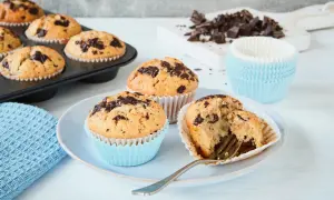 Schokoladenmuffins, frisch gebacken nach einem einfachen Muffins Rezept. Ein Muffin ist angeschnitten und zeigt die saftige Krume.