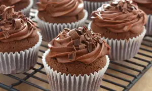 Schoko cupcakes mit cremiger Schokoladenfüllung und Schokostreuseln, auf einem Gitterrost.