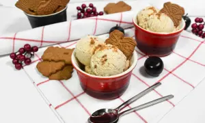 Leckeres Spekulatius Eis selber machen? Hier sind zwei Schalen mit cremigem Eis, garniert mit Spekulatius und roten Beeren.