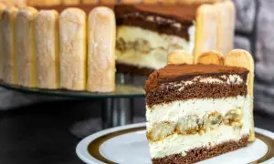 Ein köstliches Stück Tiramisu Torte mit Löffelbiskuits und Kakao bestäubt.