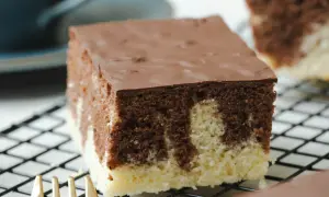 Ein Stück saftiger Marmorkuchen vom Blech mit Schokoladenglasur auf einem Kuchengitter.
