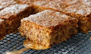 Ein saftiger karottenkuchen glutenfrei, bestäubt mit Puderzucker, wird auf einem Gitter präsentiert.