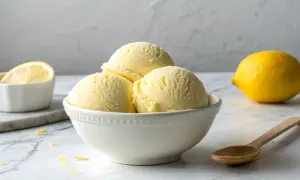Erfrischendes Limoncello Eis in einer Schale, daneben eine Zitrone und ein Löffel.