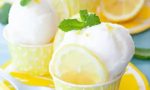 Erfrischendes Zitronensorbet-Rezept: Kugeln in gelben Tupfenförmchen, garniert mit Zitronenscheiben und Minze.