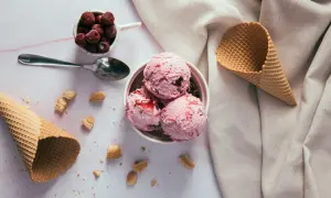 Schüssel mit rosa Eiskugeln, Kirschen und Waffelhörnchen. Ein süßer Genuss, der trotz der Kalorien verlockt.