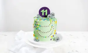 Eine bunte kinder torte für den 11. Geburtstag mit Perlenketten, Disco-Kugeln und Blumen.