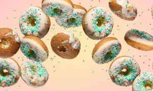 Bunte Donuts mit weißer Glasur und Streuseln schweben im Bild. Ein köstliches Rezept für selbstgemachte Donuts.