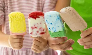 Vier Kinderhände halten bunte Fruchteis am Stiel: gelb, rot-weiß, blau-grün und braun.